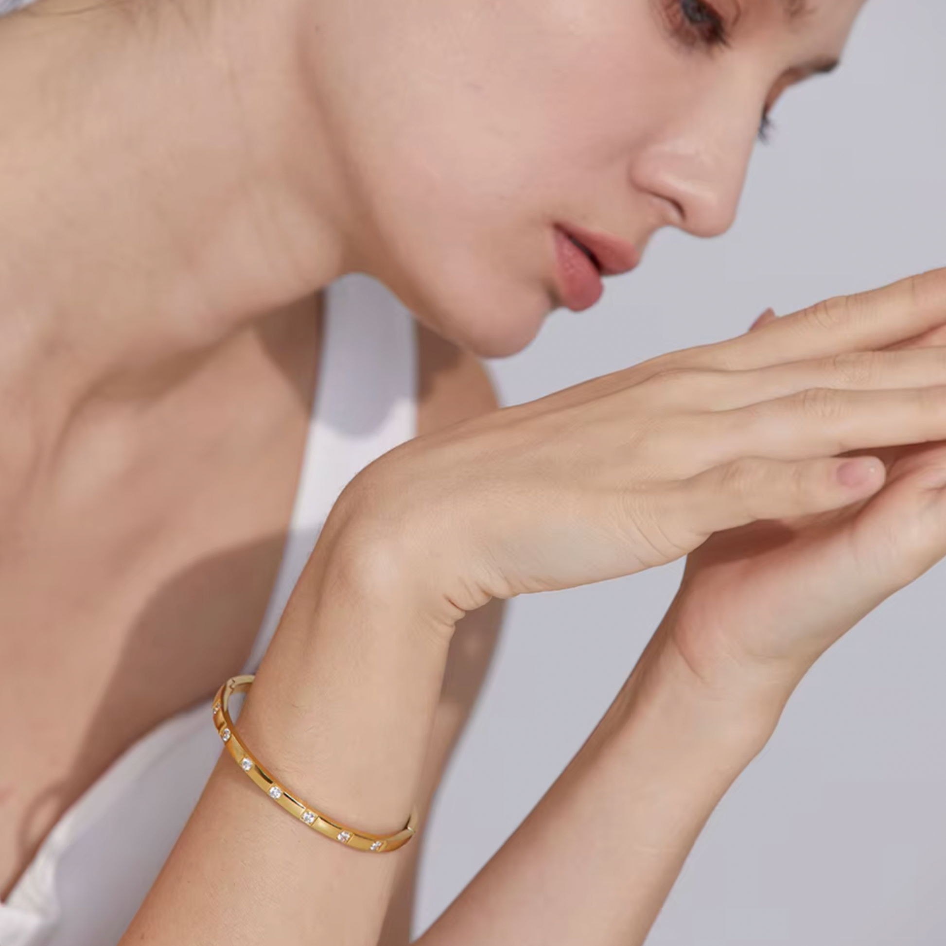 Woman wearing a gold bracelet on a plain background