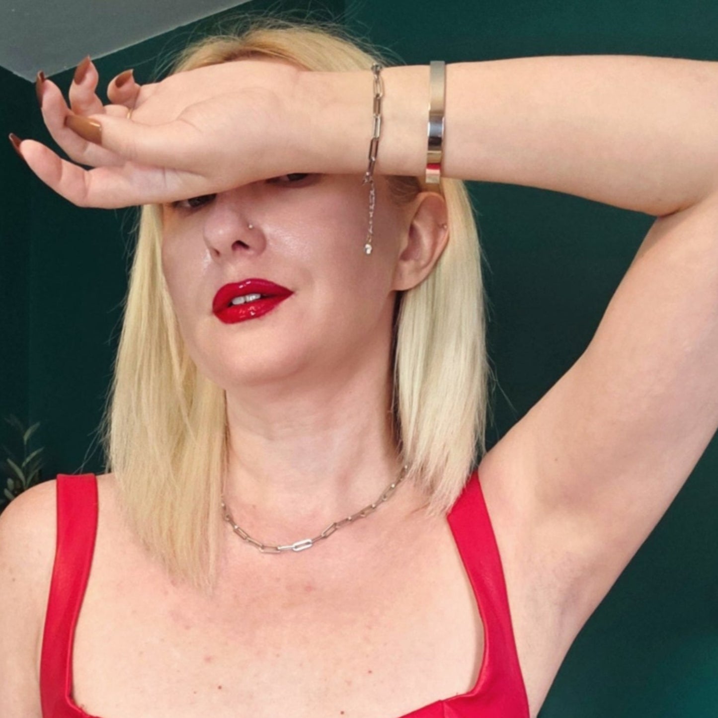 Woman in a red dress with red lipstick against a teal wall