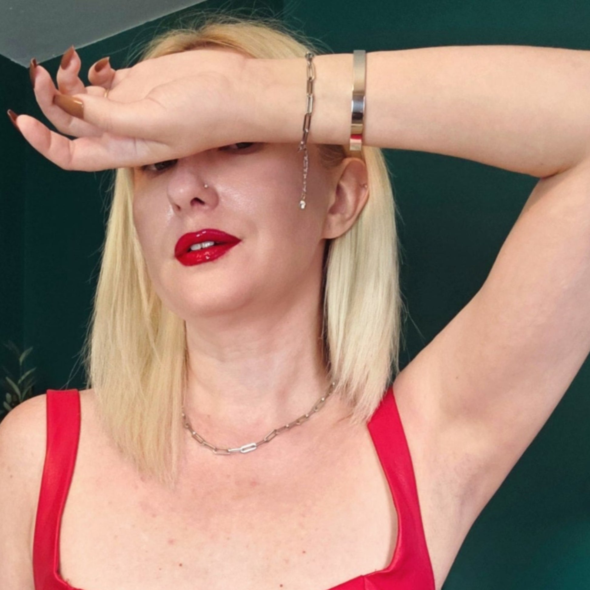 Woman in a red dress with red lipstick against a teal wall